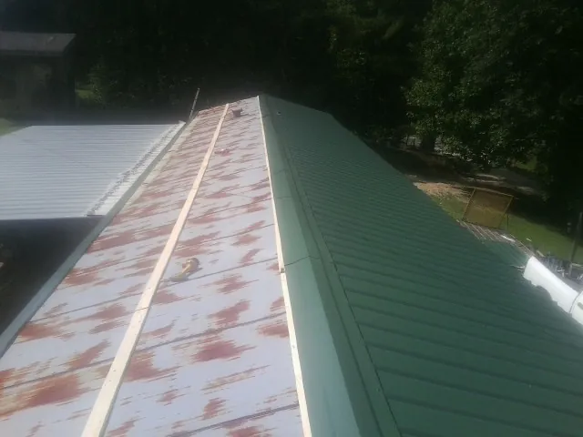 Old rusted panels beside newly installed green metal roofing — Wind Damage Roof Repair by Roofing Brothers in Prague