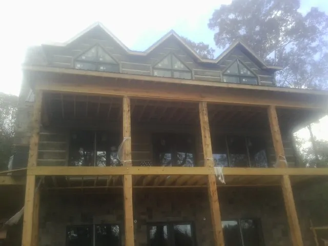Dormers and porch framing on a large log home under construction — Roof Coating work by our crew in Prague